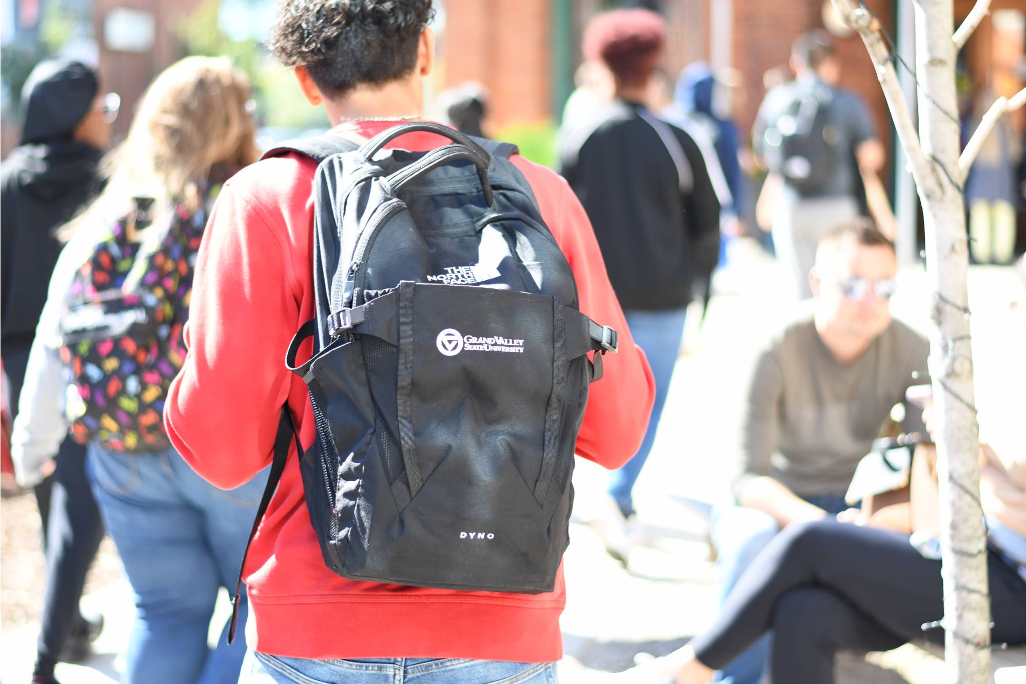 photo of student walking with Grand Valley State University backpack on through a crowd